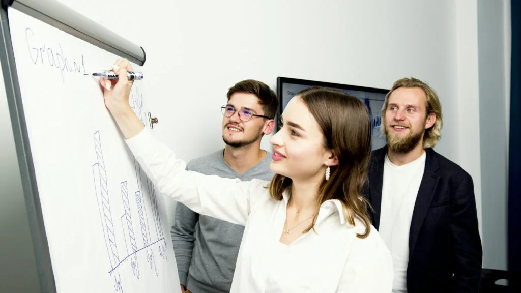 Three professionals collaborating on a business graph presentation in an office setting.